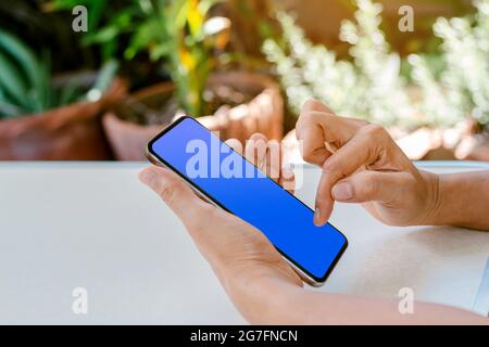 Hand der menschlichen Berührung auf blauem Bildschirm des Smartphones, Verwendung für die Verwendung von Technologie und Social-Media-Konzept. Stockfoto
