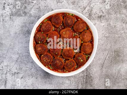 Hausgemachte Fleischbällchen mit Tomatensauce in einer weißen Backform auf dunkelgrauem Hintergrund. Draufsicht, flach liegend Stockfoto