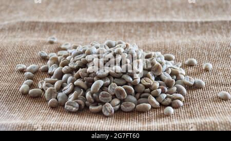 Kaffeekörner mit grünem Blatt in Sacktuch Stockfoto