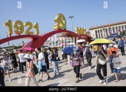 Peking, China. Juli 2021. Auf dem Platz des Himmlischen Friedens in Peking gehen Touristen unter dem Emblem der Kommunistischen Partei.nach dem Treffen zum 100. Jahrestag der Gründung der Kommunistischen Partei Chinas am 1. Juli, Auf dem Platz des Himmlischen Friedens befinden sich noch immer Landschaften wie die Jahreszahl des Parteiemblems der Kommunistischen Partei Chinas. Touristen sind gespannt auf den Platz des Himmlischen Friedens. Um den Bedürfnissen der Massen gerecht zu werden, ist die Landschaft des Tiananmen-Platzes bis Juli 31 reserviert. Quelle: Sheldon Cooper/SOPA Images/ZUMA Wire/Alamy Live News Stockfoto