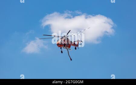 Griechenland, Athen. 13. Juli 2021. Erickson Sikorsky Air Crane Hubschrauber der griechischen Feuerwehr, in Aktion, um ein Feuer zu löschen, blauer Himmel Hintergrund. Stockfoto