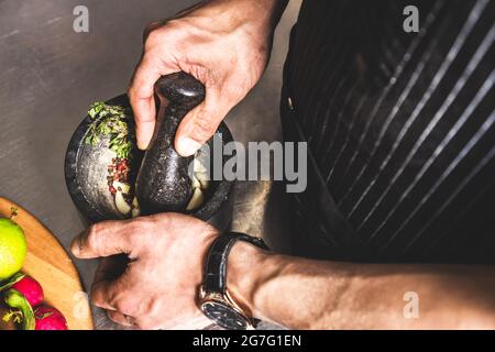 Professionelle Kochkunst im Küchenrestaurant des Hotels, Abendessen zubereiten. Ein Koch in einer Schürze macht einen Salat mit Gemüse und Pizza. Stockfoto