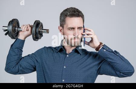 Kommunikation. Gutaussehender Geschäftsmann mit Hantel sprechen am Telefon. Digitaler Sport. Stockfoto