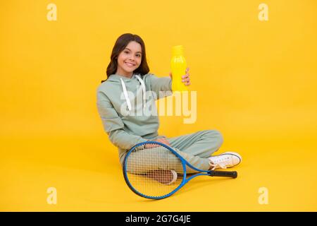 Kind mit Tennisschläger. Jugendliches Mädchen trinken Wasser nach dem Sporttraining. Badmintonspieler entspannen. Stockfoto