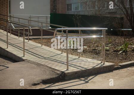 Handläufe für Personen mit eingeschränkter Mobilität. Rollstuhlgerecht. Spezielle Handläufe für Menschen. Barrierefreie Umgebung am Eingang zum Gebäude. Stockfoto