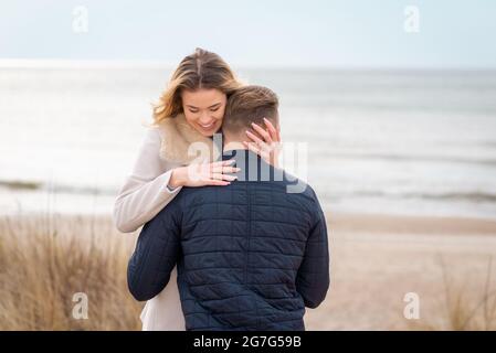 Junge schöne stilvolle Paar im Frühjahr am Strand. Umarmen Sie sich und genießen Sie einen warmen Frühlingsabend.Nahaufnahme. Stockfoto