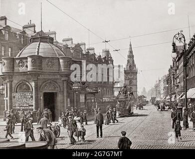 Eine Ansicht aus dem späten 19. Jahrhundert von Trongate, einer der ältesten Straßen der Stadt Glasgow, Schottland. Der Tron-Turm ist in der Ferne zu sehen und links befindet sich ein verziertes achteckiges Gebäude, das den Eingang zum Bahnhof Glasgow Cross bietet, dessen Plattformen sich unterhalb der Straßenebene befanden, Teil des Gebäudes der Caledonian Railway, das 1886 von J. J. Burnett entworfen wurde. Stockfoto