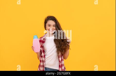 Schönheit. Kind verwenden Duschgel. Happy teen Mädchen mit Shampoo-Flasche. Haarwäsche im Salon Stockfoto