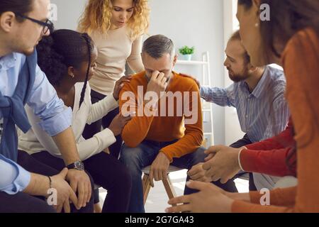 Verschiedene Menschen in der Gruppentherapie tröstlich reifen Mann, der durch Lebensprobleme geht Stockfoto