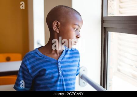 Gelangweilter afroamerikanischer Schuljunge, der im Klassenzimmer aus dem Fenster schaut Stockfoto