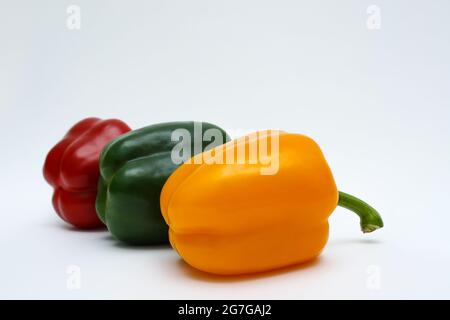 Drei Paprika (gelb, grün und rot) auf weißem Hintergrund. Paprikamischung, bulgarischer Pfeffer, vegetarisches Konzept Stockfoto