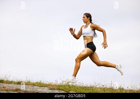 Entschlossene Sportlerin, Die Auf Dem Berg Gegen Den Himmel Läuft Stockfoto