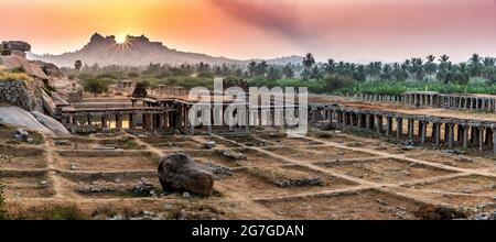 Blick auf Sonnenaufgang in Pushkarni, Sri Krishna Tank in Ruinen. südseite des Pools mit Schrein. Felsbrocken und Berge am Horizont. Hampi, Karnataka, Indien. Stockfoto