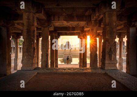 Blick auf Sonnenaufgang in Pushkarni, Sri Krishna Tank in Ruinen. südseite des Pools mit Schrein. Felsbrocken und Berge am Horizont. Hampi, Karnataka, Indien. Stockfoto