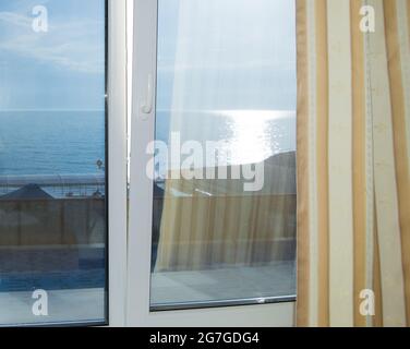 Vorhänge am Fenster, Meerblick bei Sonnenuntergang, Silberpfad, Sommerabend. Stockfoto