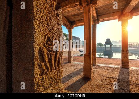 Blick auf Sonnenaufgang in Pushkarni, Sri Krishna Tank in Ruinen. südseite des Pools mit Schrein. Felsbrocken und Berge am Horizont. Hampi, Karnataka, Indien. Stockfoto