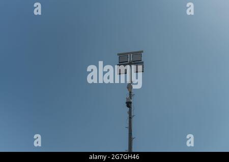 Ein Straßenmast mit Überwachungskameras, in einer kriminellen Zone und Nachtlicht-Lampen. Gegen den blauen Himmel. Stockfoto