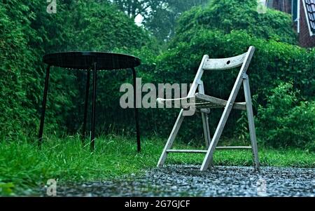 Ein leerer Stuhl in einem Garten während eines Gewitters Stockfoto