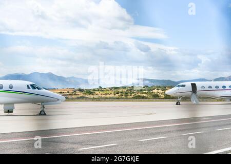 Blick auf ein Feuer in der Nähe des Flughafens Olbia Costa Smeralda mit Flugzeugen, die auf der Start- und Landebahn abgestellt sind Stockfoto