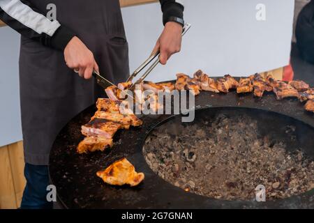 Koch hält Messer und schneidet frische, saftige Fleischsteaks auf dem Brazier aus nächster Nähe Stockfoto