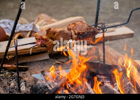 Prozess des Kochens großer Fleischstücke auf Spieß über offenem Feuer Stockfoto