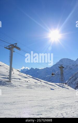 Die Stützen der Seilbahn am Skigebiet. Es gibt einen blauen Himmel und eine helle Sonne auf dem Hintergrund. Das Konzept der aktiven Winterrekreation Stockfoto