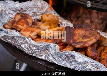 Prozess des Kochens von Steaks, Würstchen und Kartoffeln in Folie auf dem Brazier Stockfoto