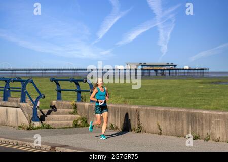 Southport, Merseyside. Vereinigtes Königreich Wetter 14 Juli 2021. Der Sommerhimmel und die leichten Winde im Badeort, während die Menschen am frühen Morgen die Sonne an der Strandpromenade genießen. Kredit; MediaWorldImages/AlamyLiveNews Stockfoto