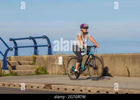 Southport, Merseyside. Vereinigtes Königreich Wetter 14 Juli 2021. Der Sommerhimmel und die leichten Winde im Badeort, während die Menschen am frühen Morgen die Sonne an der Strandpromenade genießen. Kredit; MediaWorldImages/AlamyLiveNews Stockfoto