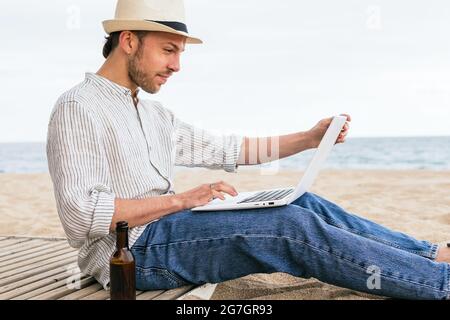 Inhalt älterer männlicher Gärtner mit Hacke in den Händen, der auf die Kamera schaut, während er in der Nähe einer grünen Pflanze mit Tomaten auf dem Land steht Stockfoto