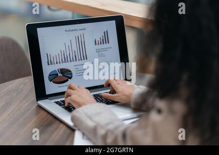 Geschäftsfrau arbeitet mit Finanzcharts, die an einem Tisch in einem Café sitzen. Stockfoto