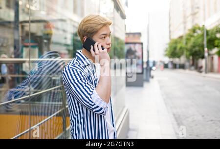 Asiatischer Mann im Gespräch mit einem Handy in der Stadt Straße Stockfoto