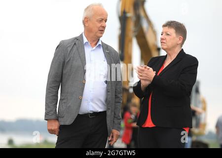 EINGEREICHT am 14. Juli 2021, Sachsen-Anhalt, Sandau: Umweltministerin Claudia Dalbert (Bündnis 90/die Grünen, r) und der Direktor der Landesagentur für Hochwasserschutz und Wasserwirtschaft, Burkhard Henning, stehen vor dem Spatenstich für die Deichschneidung auf dem alten Deich Sandau-Süd. Die vergangenen Hochwasserereignisse in den Jahren 2002 und 2013 zeigten, dass der bestehende Deich zwischen Sandau und Havelberg dringend saniert werden muss. Die Deichumsiedlung ist Teil des Nationalen Hochwasserschutzprogramms der Bundesrepublik Deutschland und des Programms "Mehr Raum für unsere Flüsse" in Sachsen-Anh Stockfoto