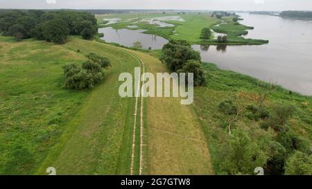 GESPEICHERT - 14. Juli 2021, Sachsen-Anhalt, Sandau: Blick auf den alten Deich Sandau-Süd an der Elbe (Luftaufnahme mit Drohne). Hier fand am Mittwoch der Spatenstich für das Deichschneiden statt. Die vergangenen Hochwasserereignisse in den Jahren 2002 und 2013 zeigten, dass der bestehende Deich zwischen Sandau und Havelberg dringend renoviert werden muss. Die Deichumsiedlung ist Teil des Nationalen Hochwasserschutzprogramms der Bundesrepublik Deutschland und des Programms "Mehr Raum für unsere Flüsse" in Sachsen-Anhalt. Durch den Umzug werden hier rund 124 Hektar Auen zurückgewinnen, verglichen mit etwa 60 Hektar Stockfoto