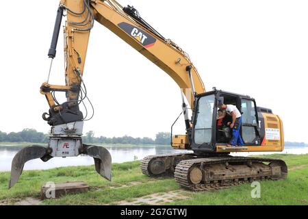 EINGEREICHT - 14. Juli 2021, Sachsen-Anhalt, Sandau: Ein Bagger steht vor dem Spatenstich für den Deichschlitz auf dem alten Deich Sandau-Süd. Die vergangenen Hochwasserereignisse in den Jahren 2002 und 2013 zeigten, dass der bestehende Deich zwischen Sandau und Havelberg dringend saniert werden muss. Die Deichumsiedlung ist Teil des Nationalen Hochwasserschutzprogramms der Bundesrepublik Deutschland und des Programms "Mehr Raum für unsere Flüsse" in Sachsen-Anhalt. Durch den Umzug werden hier rund 124 Hektar Auengebiet zurückgewinnen, im Vergleich zu rund 60 Hektar für das Sandau-Nord-Bauprojekt. Stockfoto