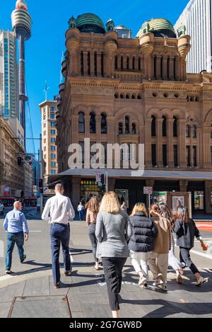 In Richtung Queen Victoria Building (QVB) und Sydney Tower überqueren die Menschen in ihrer Mittagspause die York Street an der Ampel Stockfoto