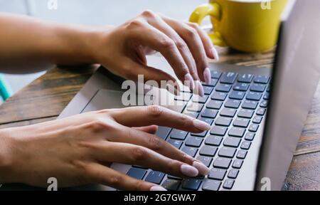 Freiberufliche Freiberuflerin, die während der Arbeit an einem Remote-Projekt auf der Café-Terrasse auf der Laptop-Tastatur tippte, wurde nicht erkannt Stockfoto