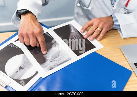 Von oben der Ernte anonymen männlichen Arzt untersucht Röntgenstrahlen, während am Tisch in der medizinischen Praxis sitzen und in der Klinik arbeiten Stockfoto