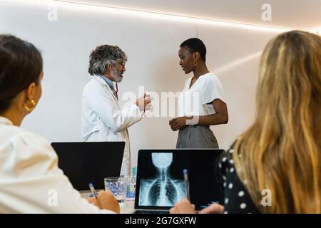 Gesellschaft von Sanitätern, die schwarze weibliche Patientin während der Verabredung in der medizinischen Abteilung der modernen Klinik untersuchen Stockfoto