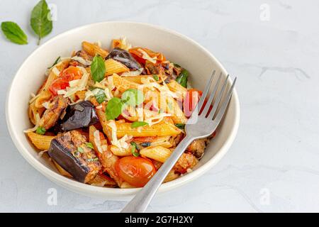 Pasta Alla Norma, sizilianische Pasta mit Aubergine garniert mit Basilikumblättern Stockfoto