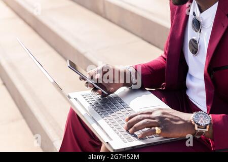 Detail der Hand eines nicht erkennbaren Geschäftsmannes mit einem Smartphone und Computer-Laptop, Technologie und Remote-Work-Konzept, Kopierraum für Text Stockfoto