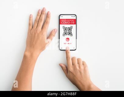 Draufsicht über der oberen Ansicht der Frau mit Smartphone mit Immunitätspass und QR-Code auf dem Bildschirm. Elektronische Gesundheitsbescheinigung Covid-19 nicht gültig. Pcr Stockfoto