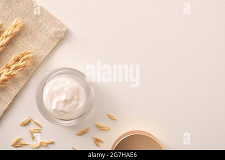 Hafer Körper und Gesichts Feuchtigkeitscreme in Glas mit Spikes auf weißem Tisch mit Sackleinen. Draufsicht. Horizontale Zusammensetzung. Stockfoto