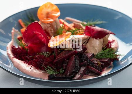 Hummus mit Gemüse, Beete-Hummus mit sautierten Gemüsestöcken und Svela-Blättern, heller Hintergrund Stockfoto