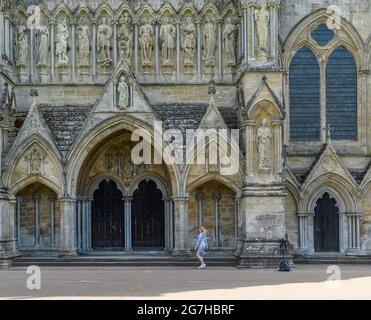 Salisbury, Wiltshire, Großbritannien, 14. Juli 2021, Wetter: Ein warmer Sommertag auf dem Gelände der Salisbury Cathedral mit Temperaturen bis in die Mitte der 20er Jahre und steigenden Temperaturen, wenn sich eine Hitzewelle aus dem Süden bildet. Eine junge Frau posiert für Selfies unter dem Blick der Nordfassade. Kredit: Paul Biggins/Alamy Live Nachrichten Stockfoto