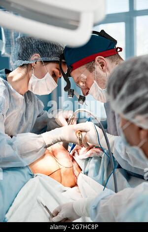 Chirurgen Männer und Frauen in einem Team während einer Operation über dem Operationstisch führen Ärzte in modernen Geräten eine onkologische Operation durch. Stockfoto