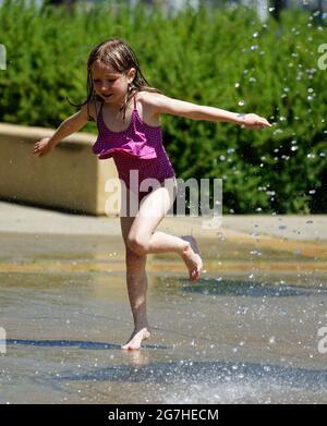 Ein kleines Mädchen (7 Jahre alt), das in Quebec City, Kanada, Wasserspiele und Springbrunnen spielt Stockfoto