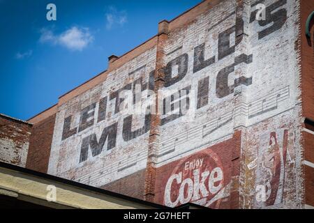 Erhaltene alte Musik und Coca-Cola-Schilder an der Seite eines Backsteingebäudes in Sioux Falls, South Dakota, USA. Stockfoto