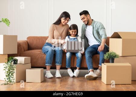 Happy Loving Family Mit Laptop Sitzen Auf Der Couch Nach Dem Umzug Ins Neue Zuhause. Immobilien, Eigentumsrecht Und Umzugskonzept. Personen, Die Im Internet Surfen Stockfoto