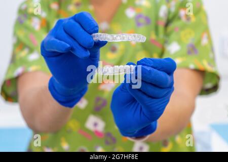 Arzt mit zwei transparenten Zahnalignern und zahnärztlicher Nachtwache. Stockfoto